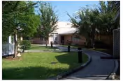 Exterior view of Atlantic Shores Nursing and Rehab Center with curved walkway and green lawn.