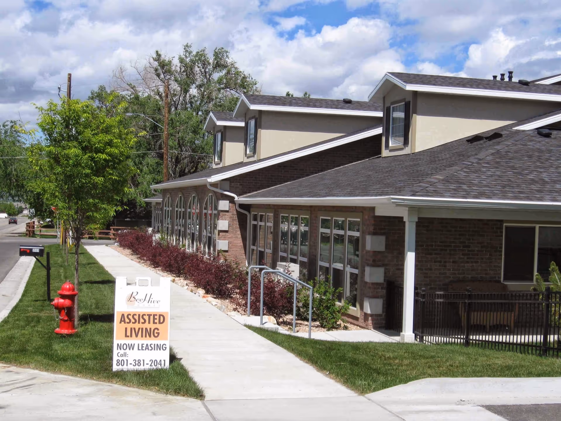 Exterior view of Beehive Homes of Draper with leasing sign and landscaping.