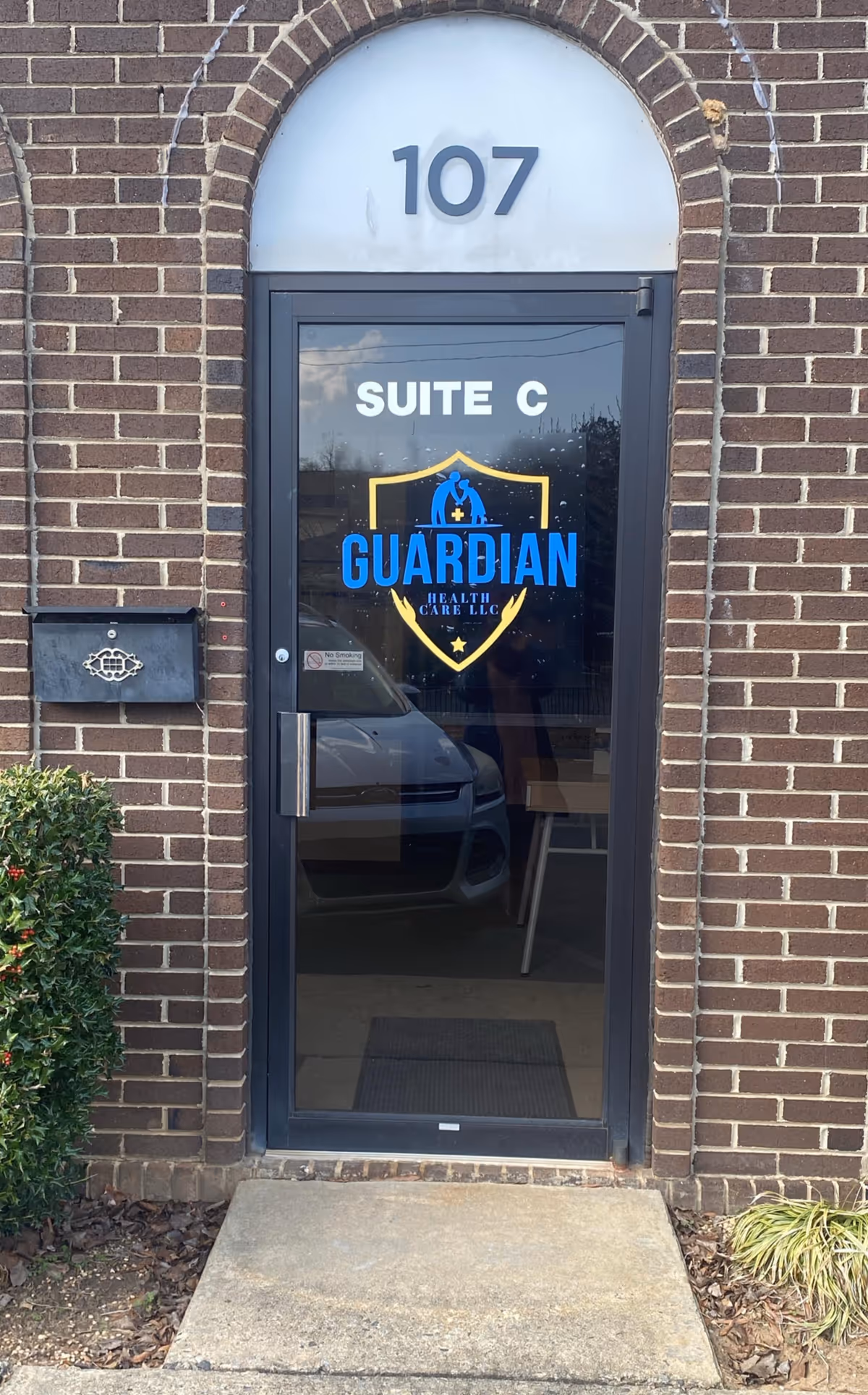 Brick building entrance with glass door labeled Suite C and Guardian Health Care LLC logo.