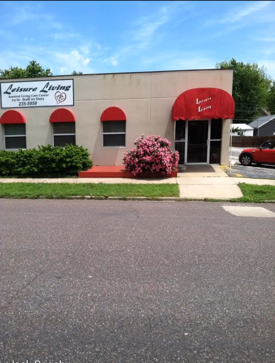 Exterior view of Leisure Living facility with red awnings and a flowering bush.