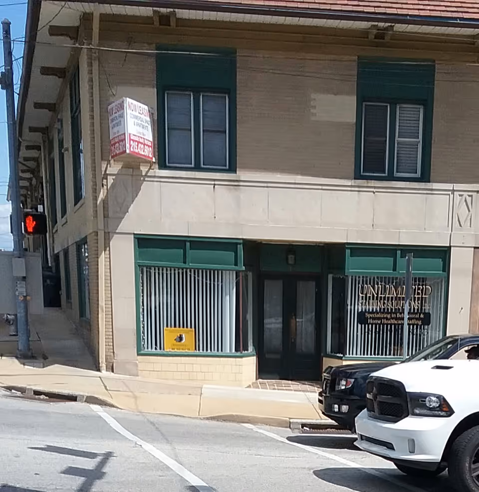 Two-story storefront labeled Unlimited Staffing Solutions on a street with teal trim.
