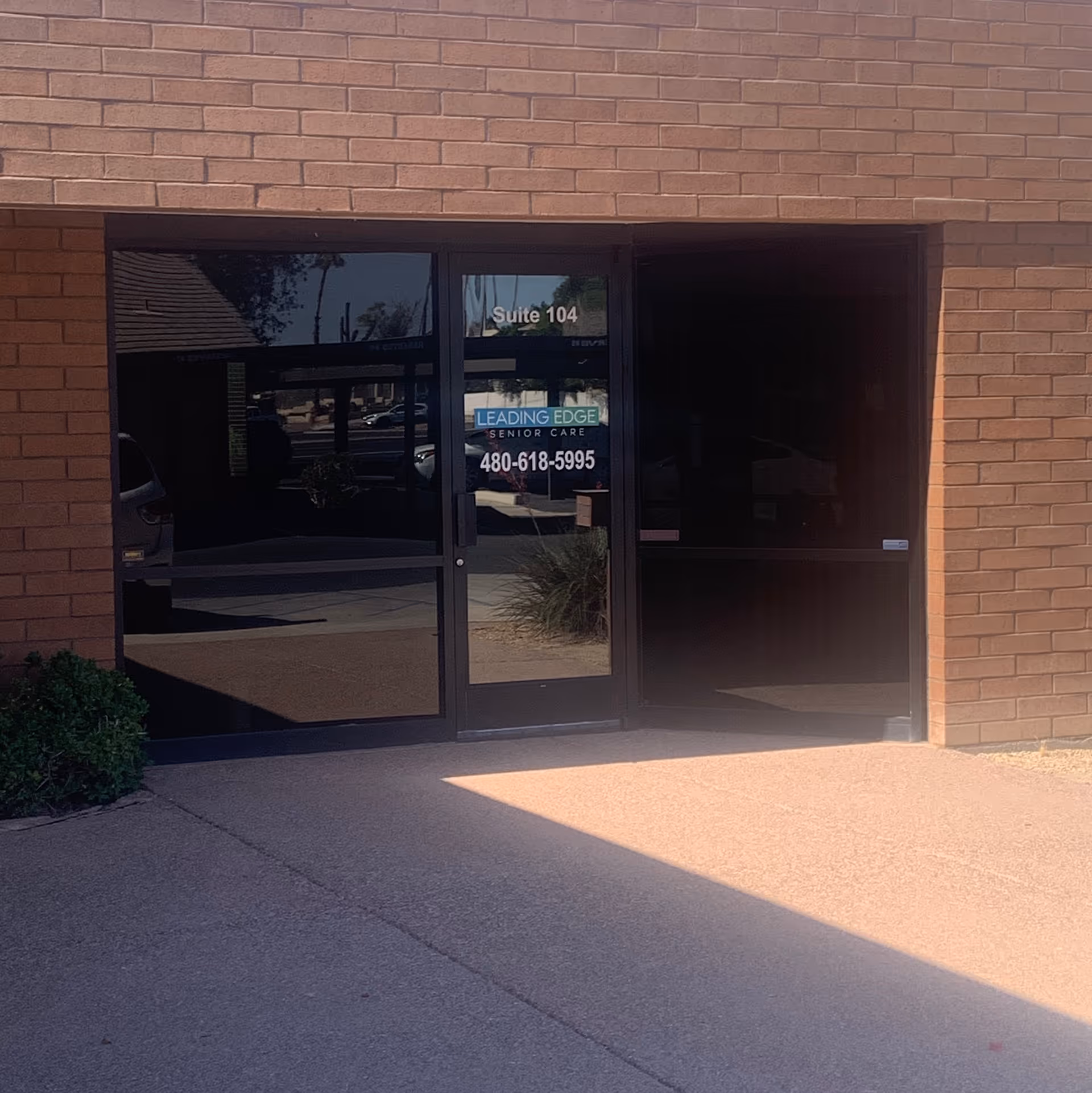 Exterior brick entrance with glass doors displaying Leading Edge Senior Care signage.