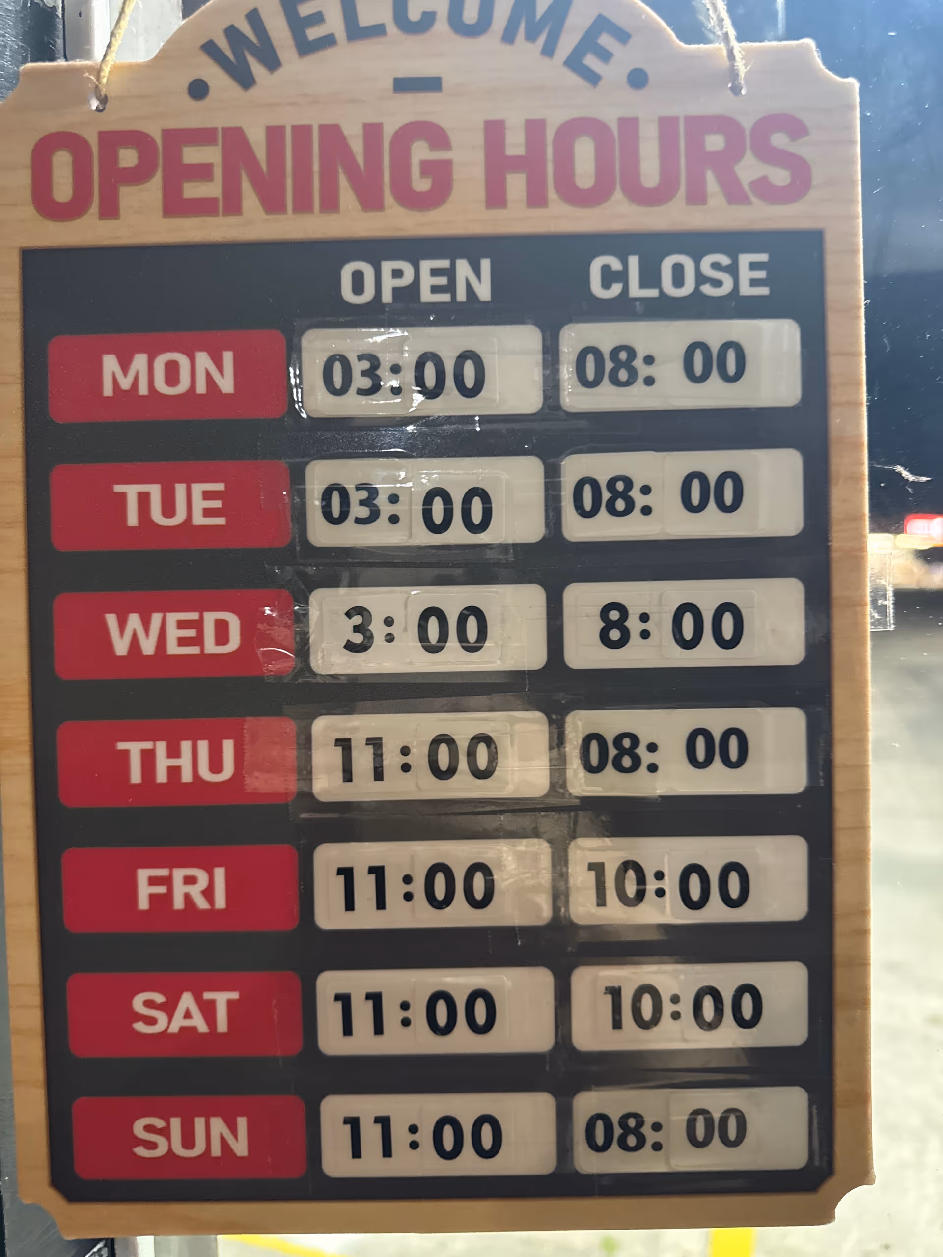 Hanging wooden sign displays weekly opening hours.