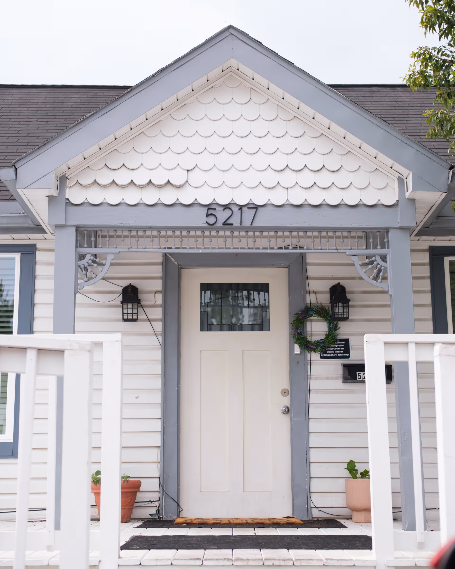 Front entrance of a light-colored building with wreath and potted plants