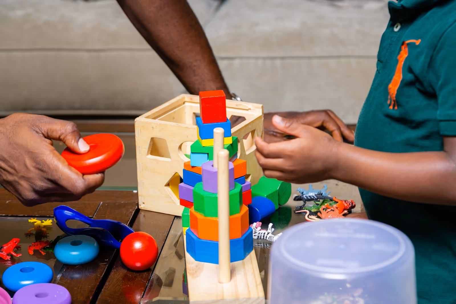 Two people play with colorful stacking blocks on a table in a therapy session.