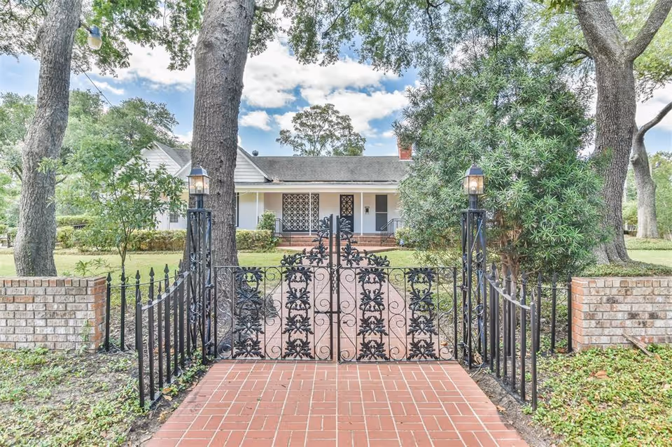 Wrought-iron gate opens onto a brick path toward a single-story assisted living home.