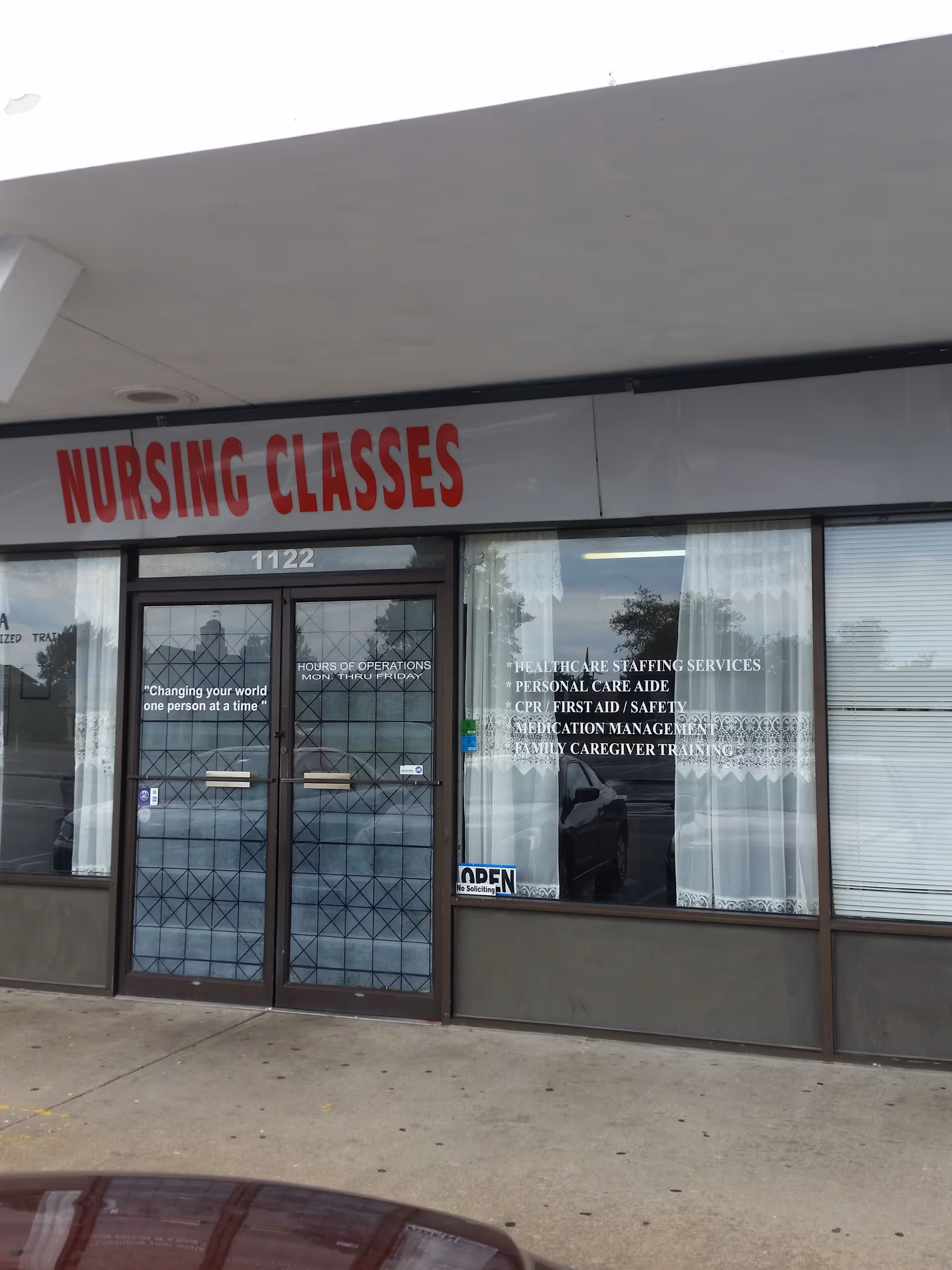 Front of a building with a large nursing classes sign above glass doors.