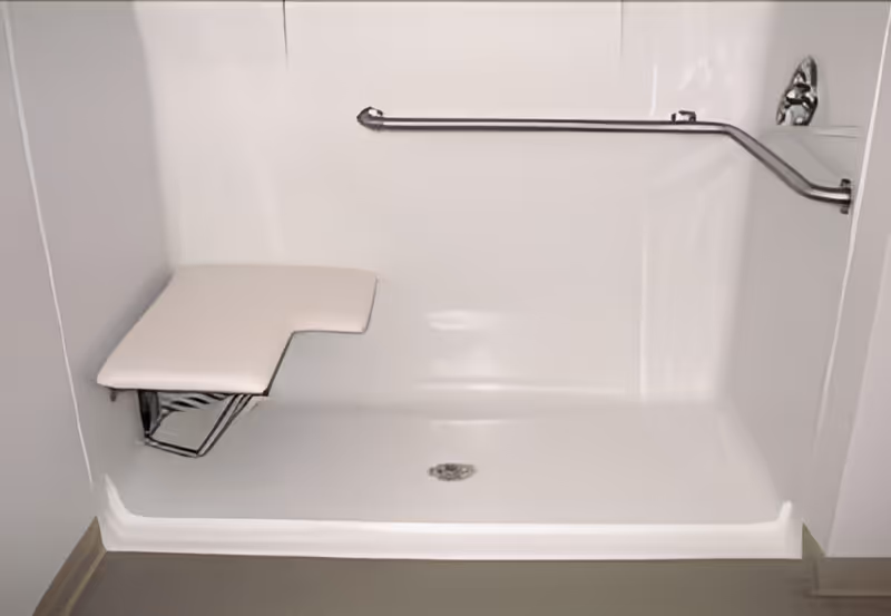 A white accessible shower stall with a fold-down seat and a horizontal grab bar mounted on the wall.