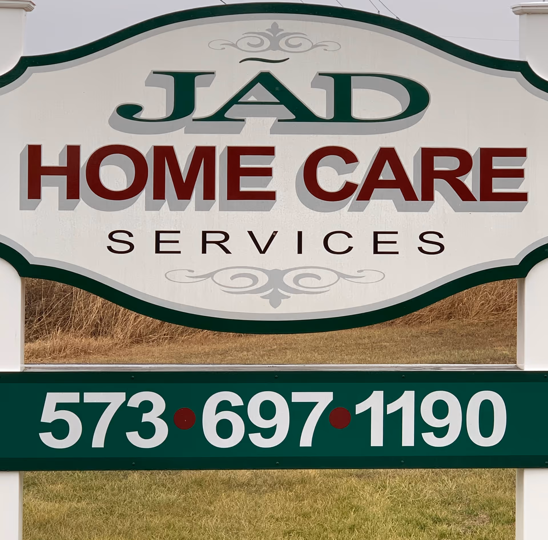 Large Jad Home Care Services sign outdoors with phone number against grassy background.