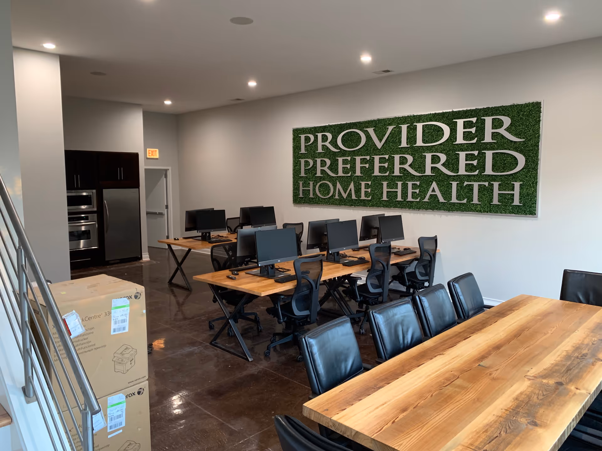 Open office area with multiple computer desks, chairs, and a green Provider Preferred Home Health sign.