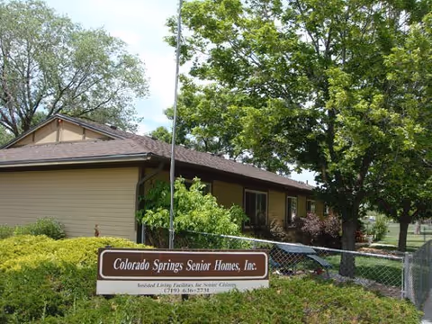Exterior view of Colorado Springs Senior Homes, Inc. building with sign and greenery.