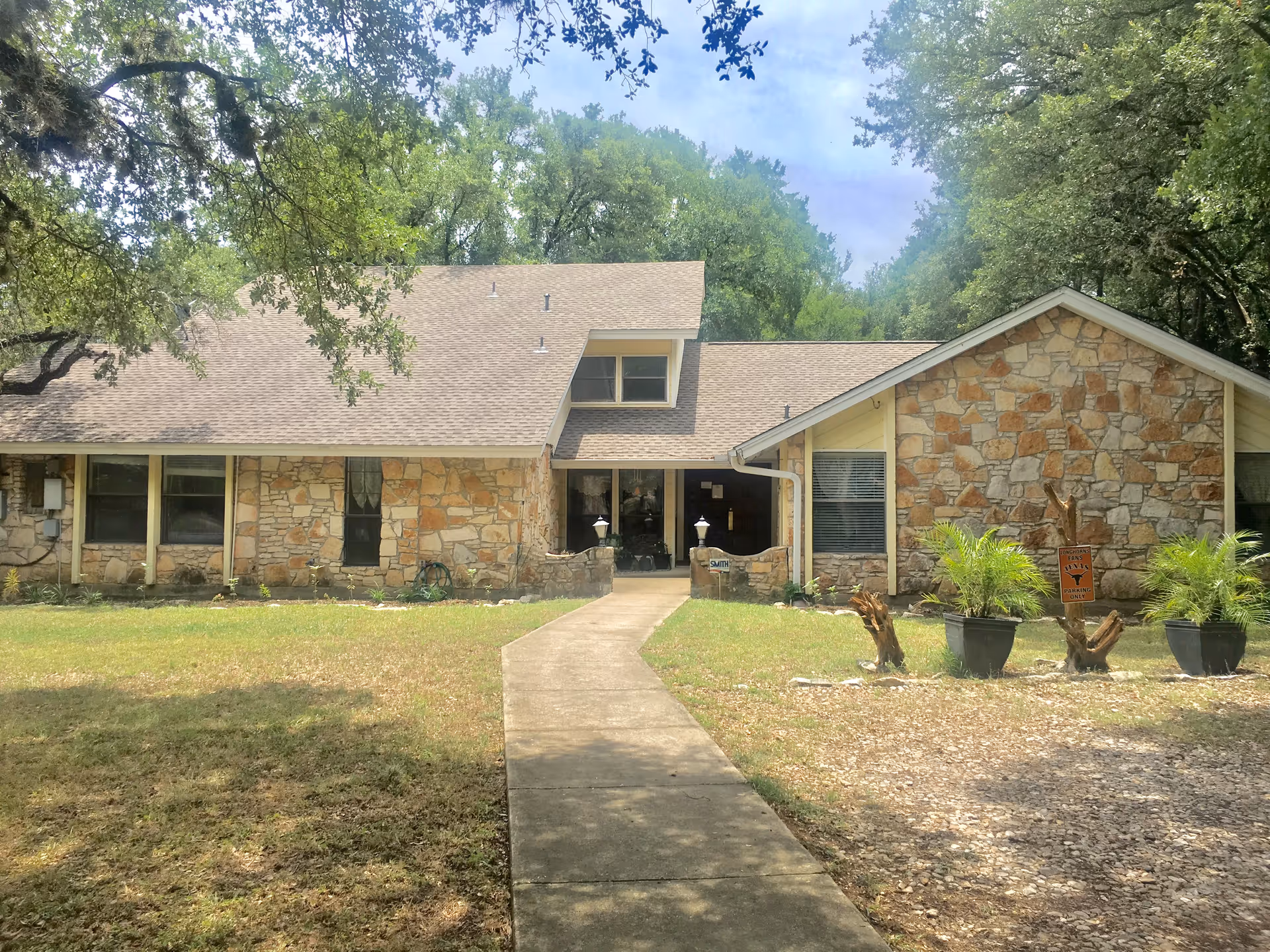 Stone-faced senior living facility with central entrance and surrounding lawn.