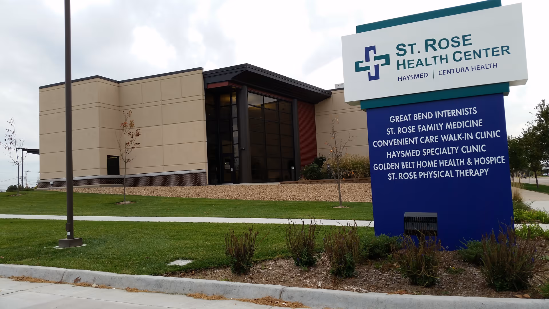 Exterior view of St. Rose Health Center with a large blue sign in the front yard.