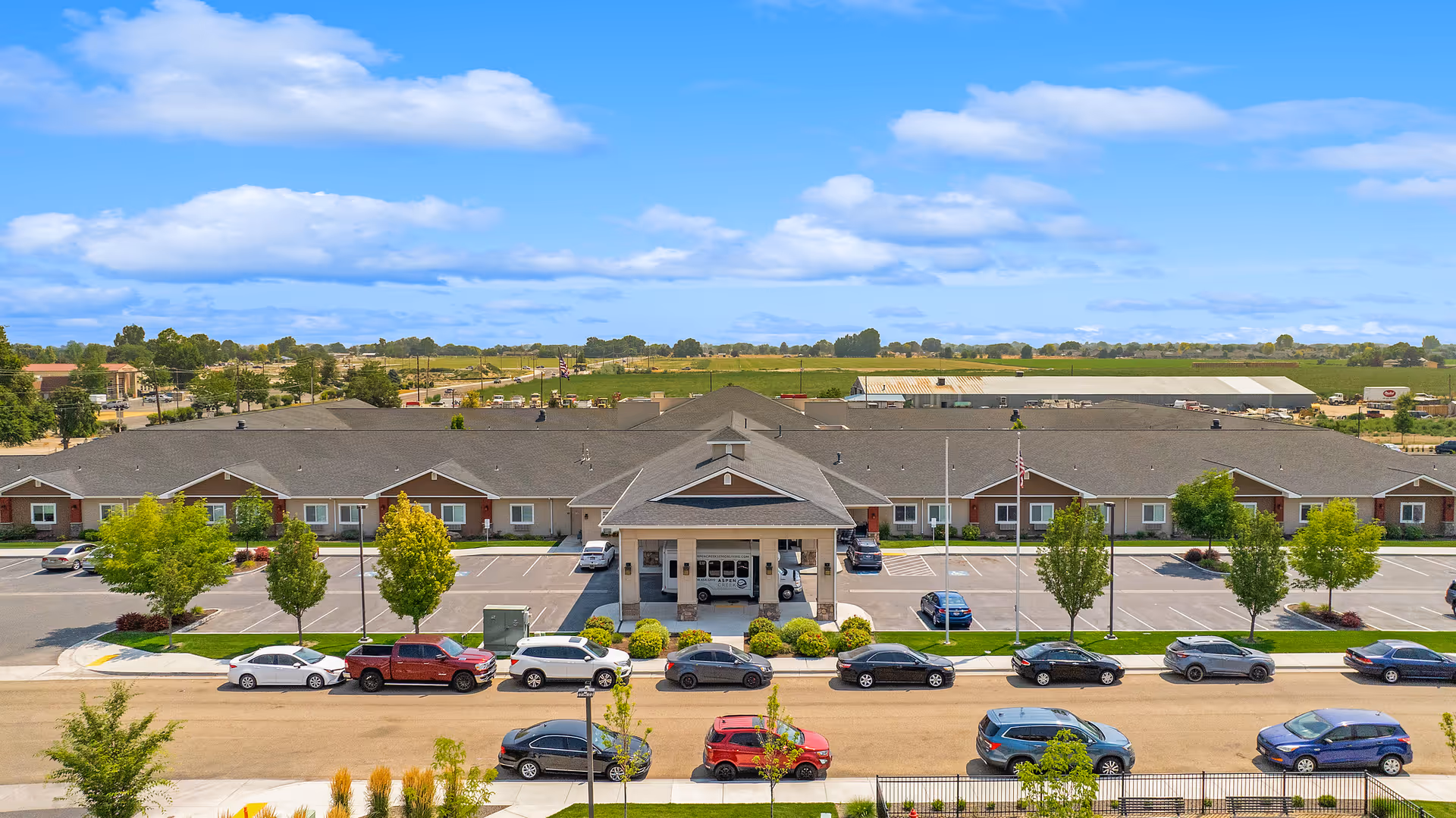 A single-story senior living campus with a covered entrance and cars parked along the front.
