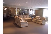 Spacious Wheatland Manor living room with beige sectional sofas and soft overhead lighting.
