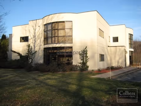 White modern senior living facility exterior with curved glass windows and landscaping