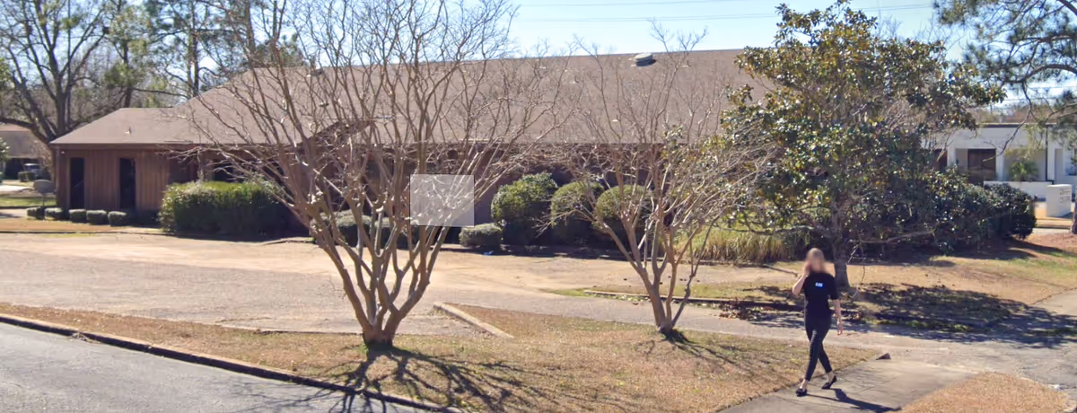 Exterior view of Innovative Homecare Services Montgomery AL building with a person walking past trees.