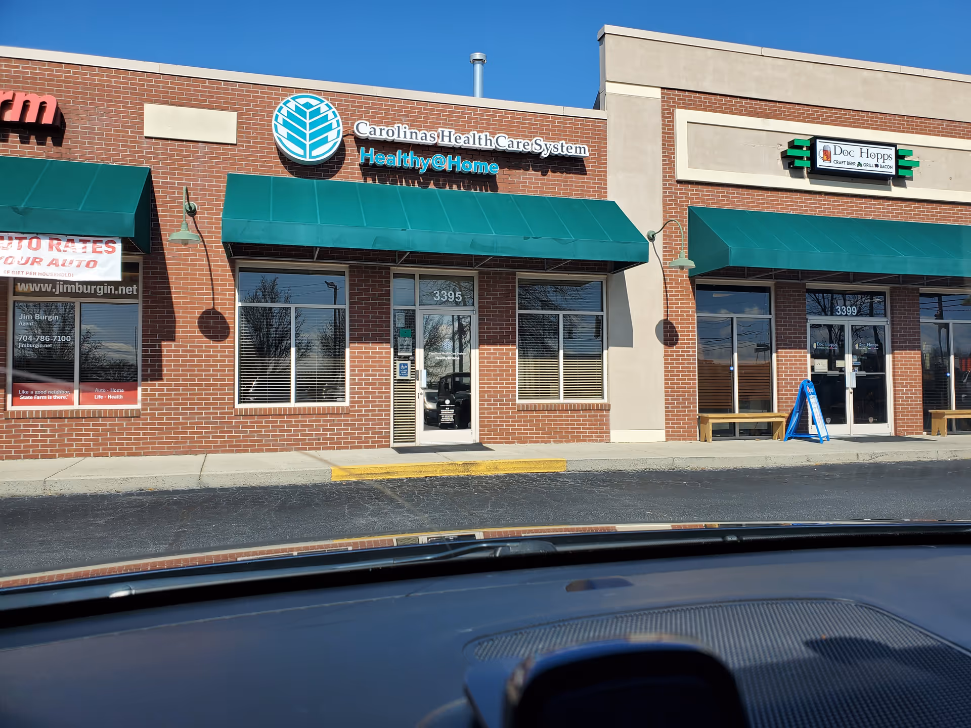 Atrium Health At Home storefront with green awnings and brick facade.