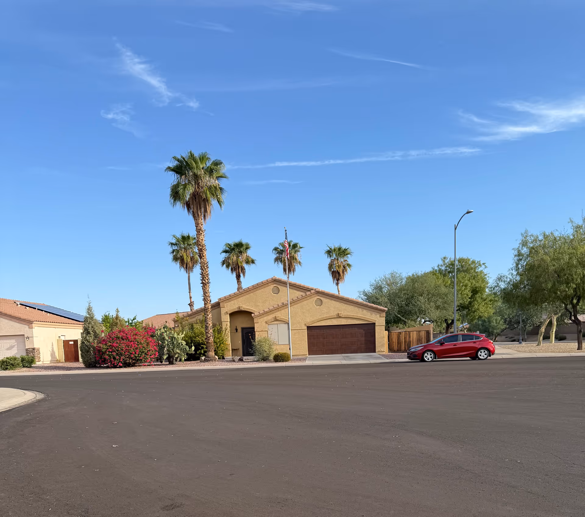 One-story beige facility with a two-car garage, palm trees, and desert landscaping.