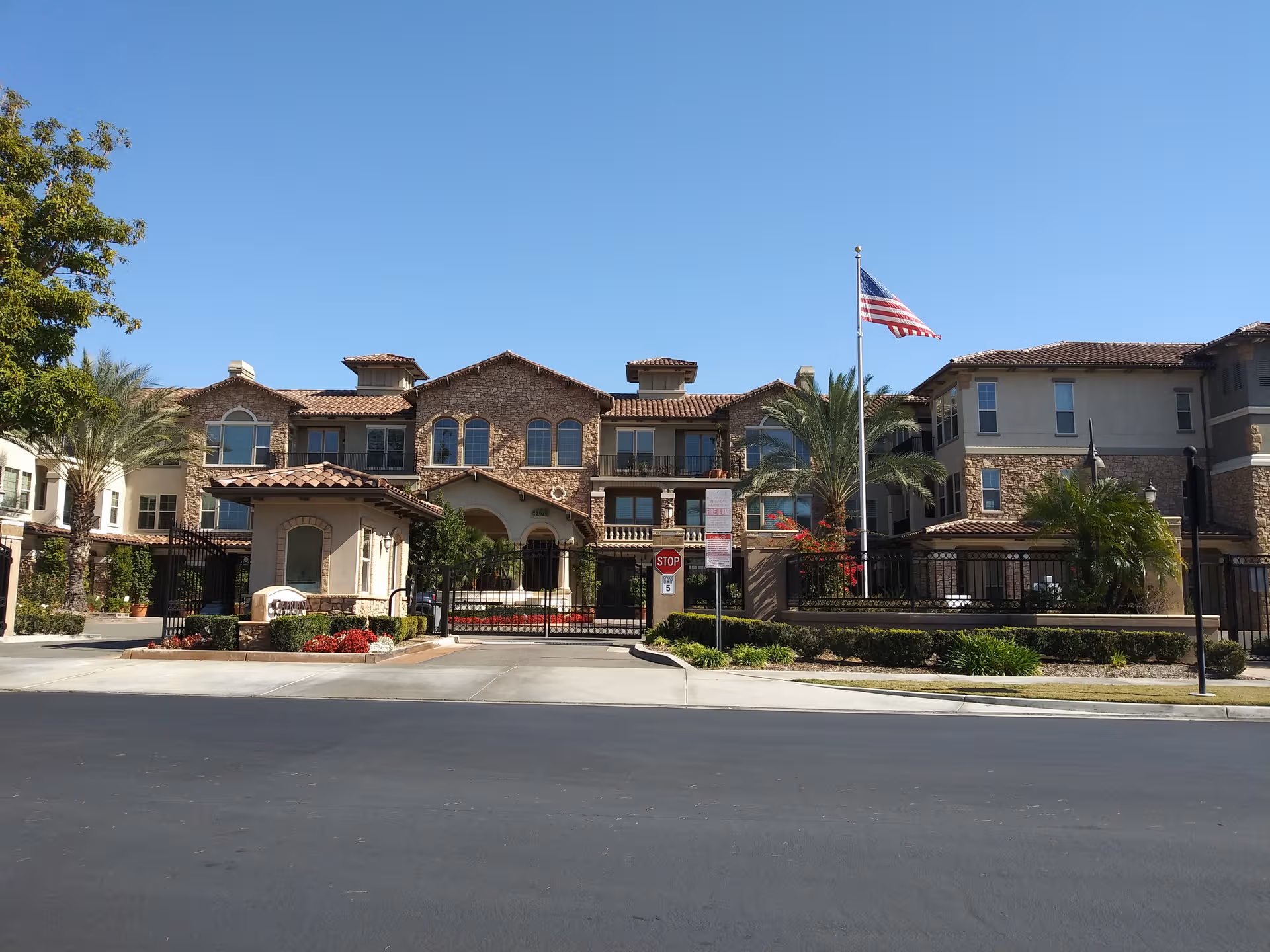 Exterior view of Capriana Retirement Living & Assisted Living building with gated entrance on sunny day.