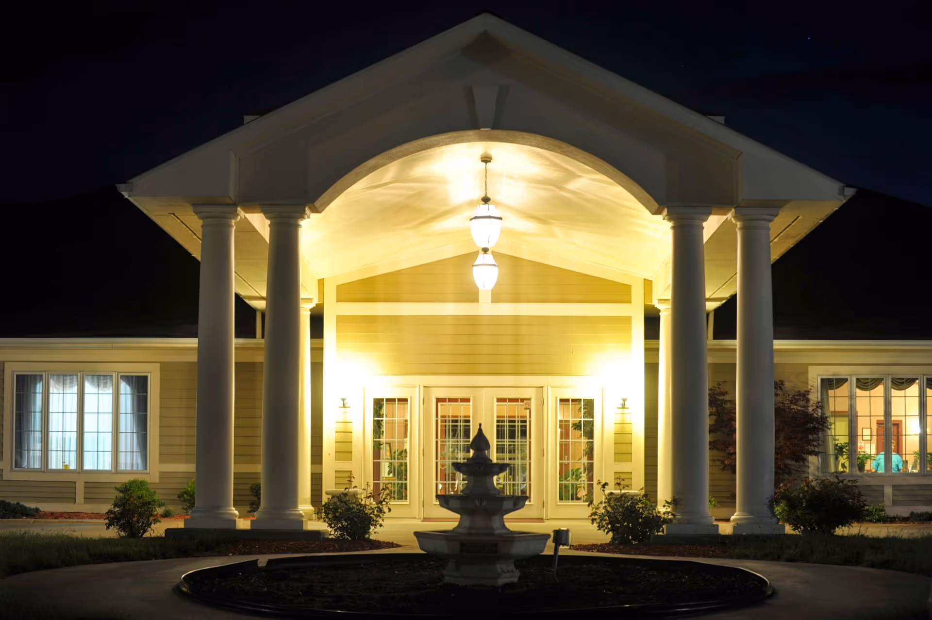 Night exterior view of Continental at St Joseph's front entrance with columns and fountain.