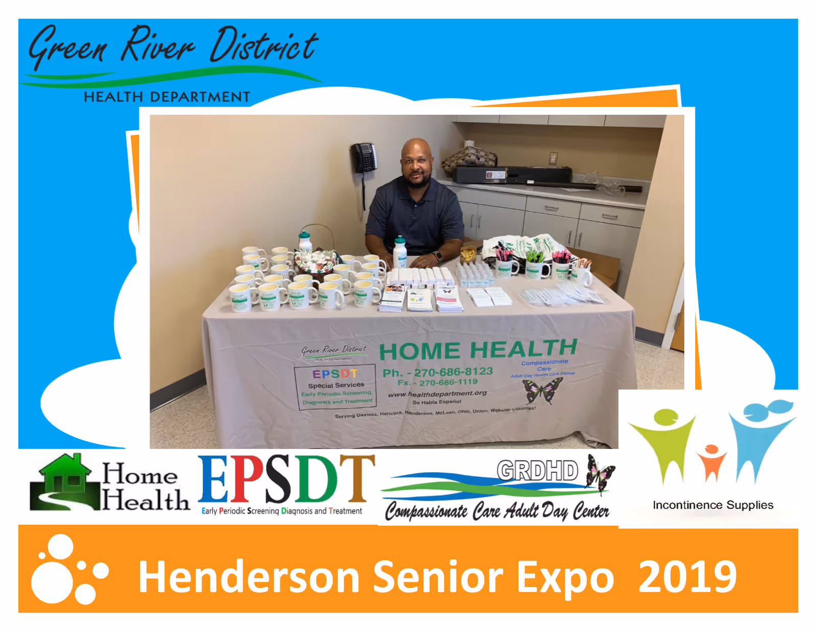 A man sits behind a table of mugs and health promotional materials indoors.