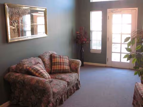 Floral sofa with plaid cushions sits in a cozy living area by the glass door.