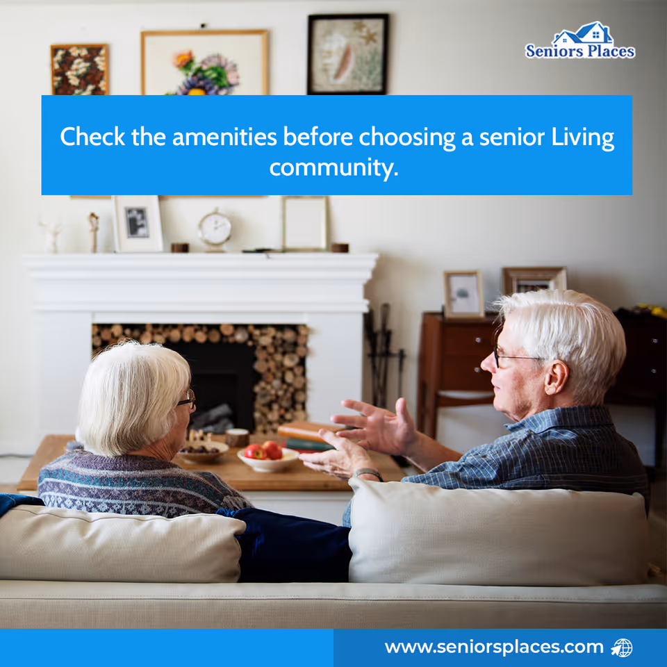 Two elderly residents sit on a sofa in a living room with a fireplace.