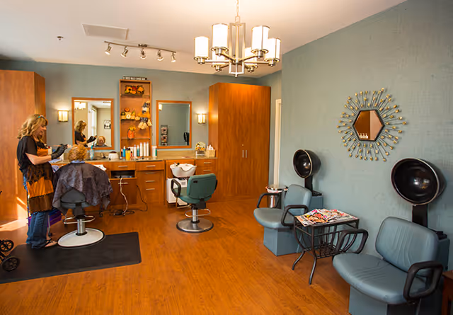 Hair salon in a senior living facility with a stylist cutting a resident's hair.