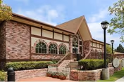 Exterior view of Victoria Care Center entrance with brick steps, arched windows, and landscaping.