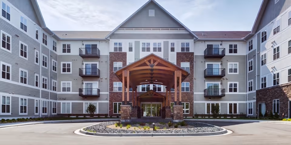 Exterior view of a senior living facility with a covered entrance and balconies.