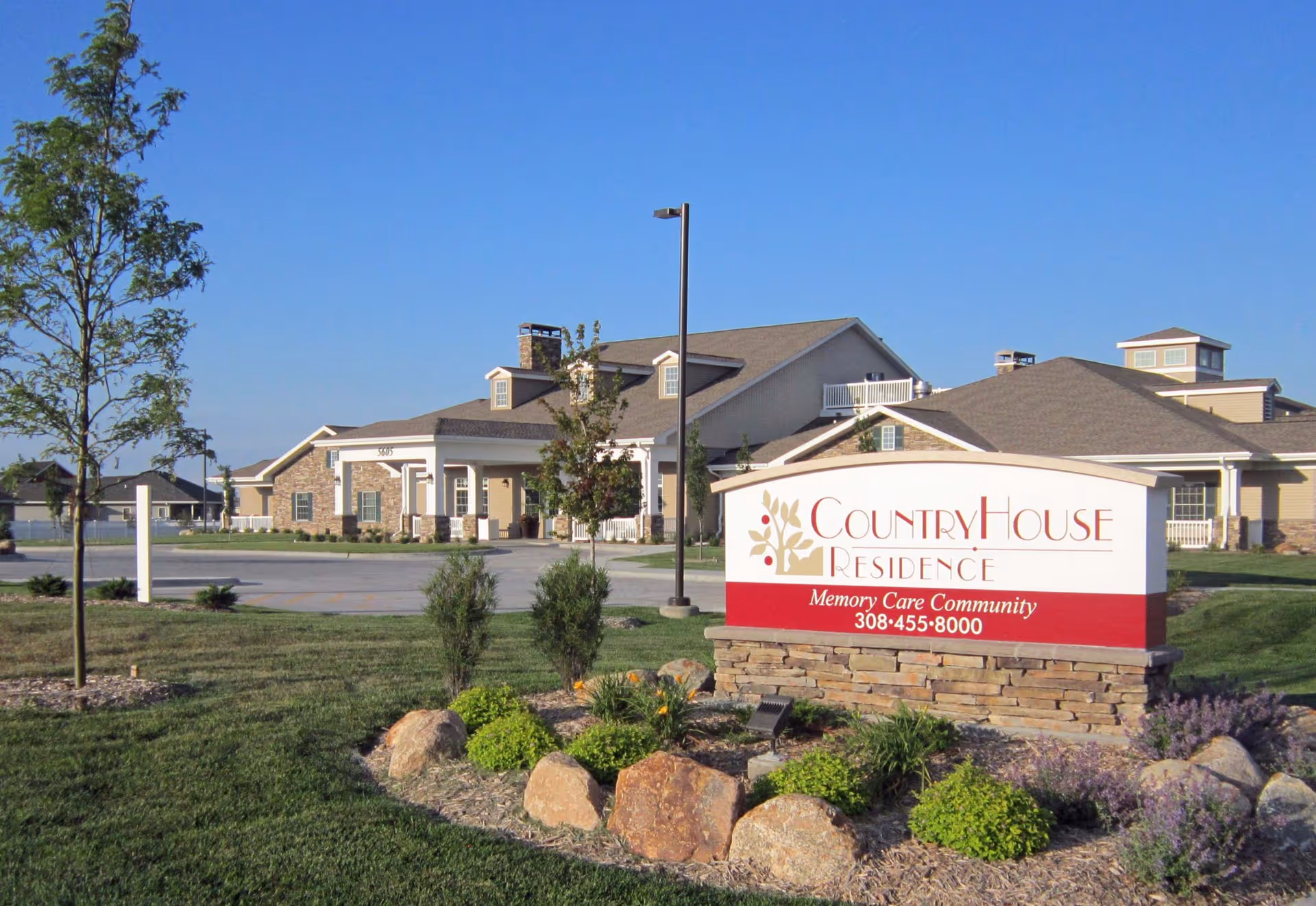 Sign for CountryHouse Residence in front of the facility's landscaped lawn and buildings under a clear blue sky.