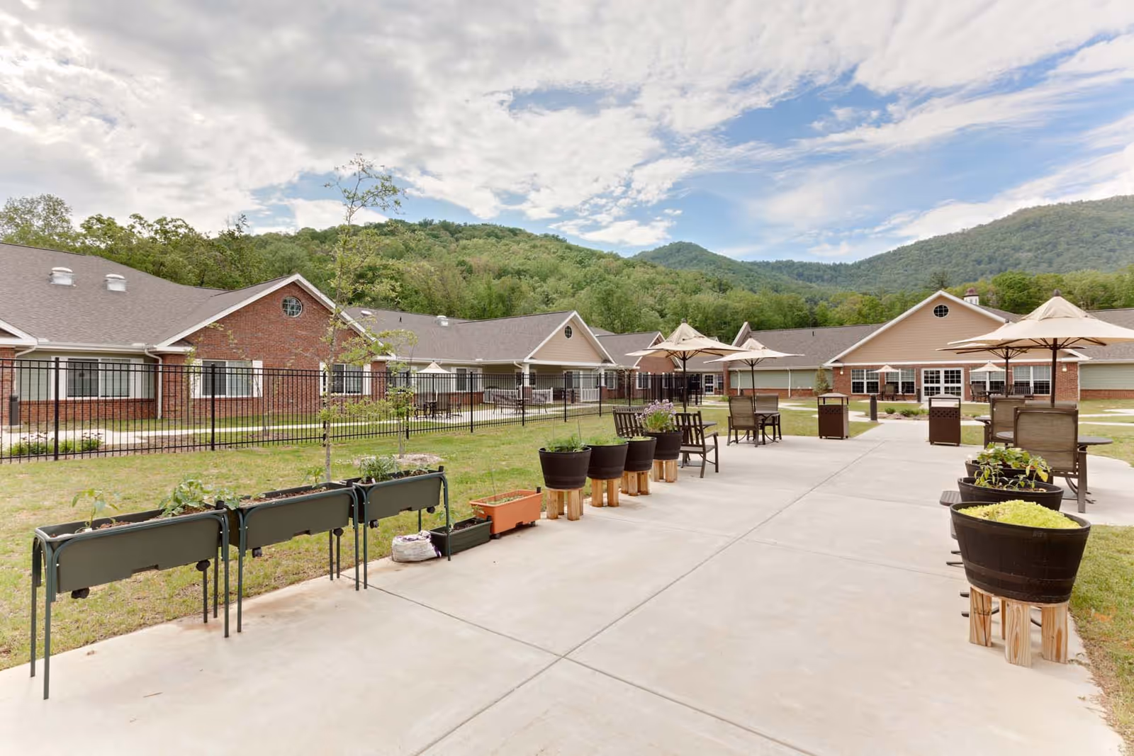 Outdoor courtyard of a veterans home with brick buildings, chairs, umbrellas, and potted planters.