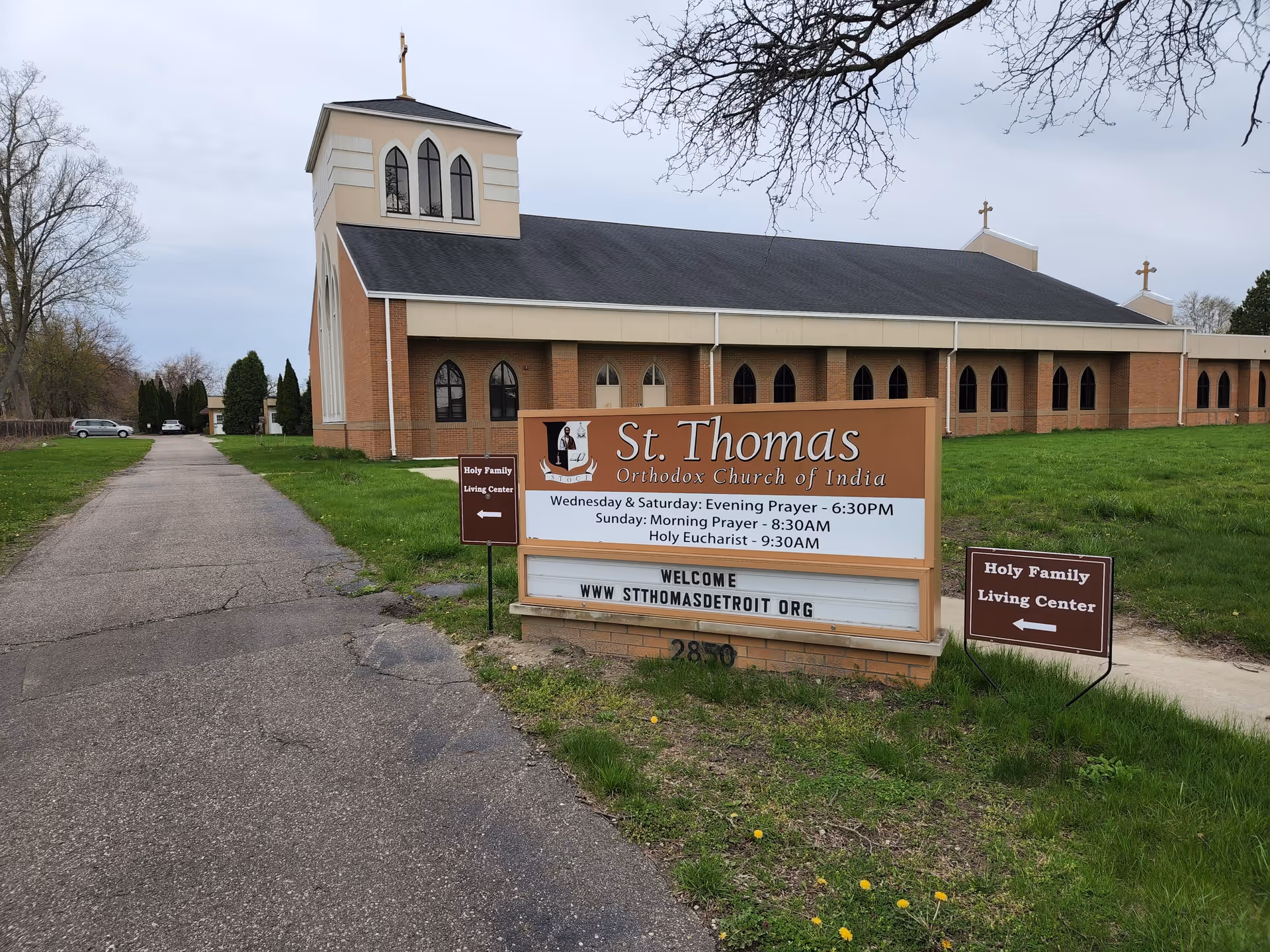 Exterior view of Holy Family Living Center church building with sign along a driveway.