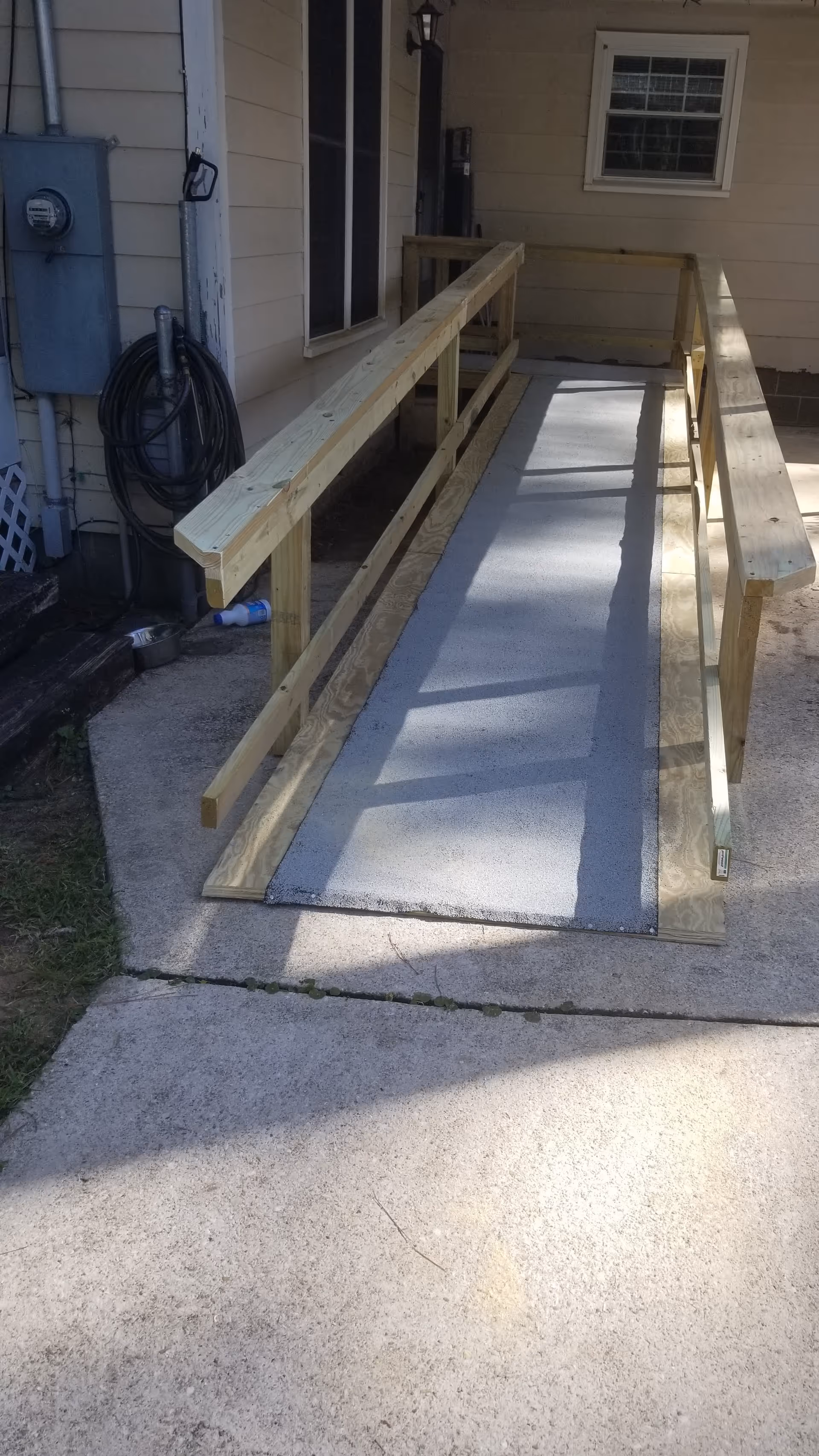 Wooden accessibility ramp with handrails leading to an exterior doorway.