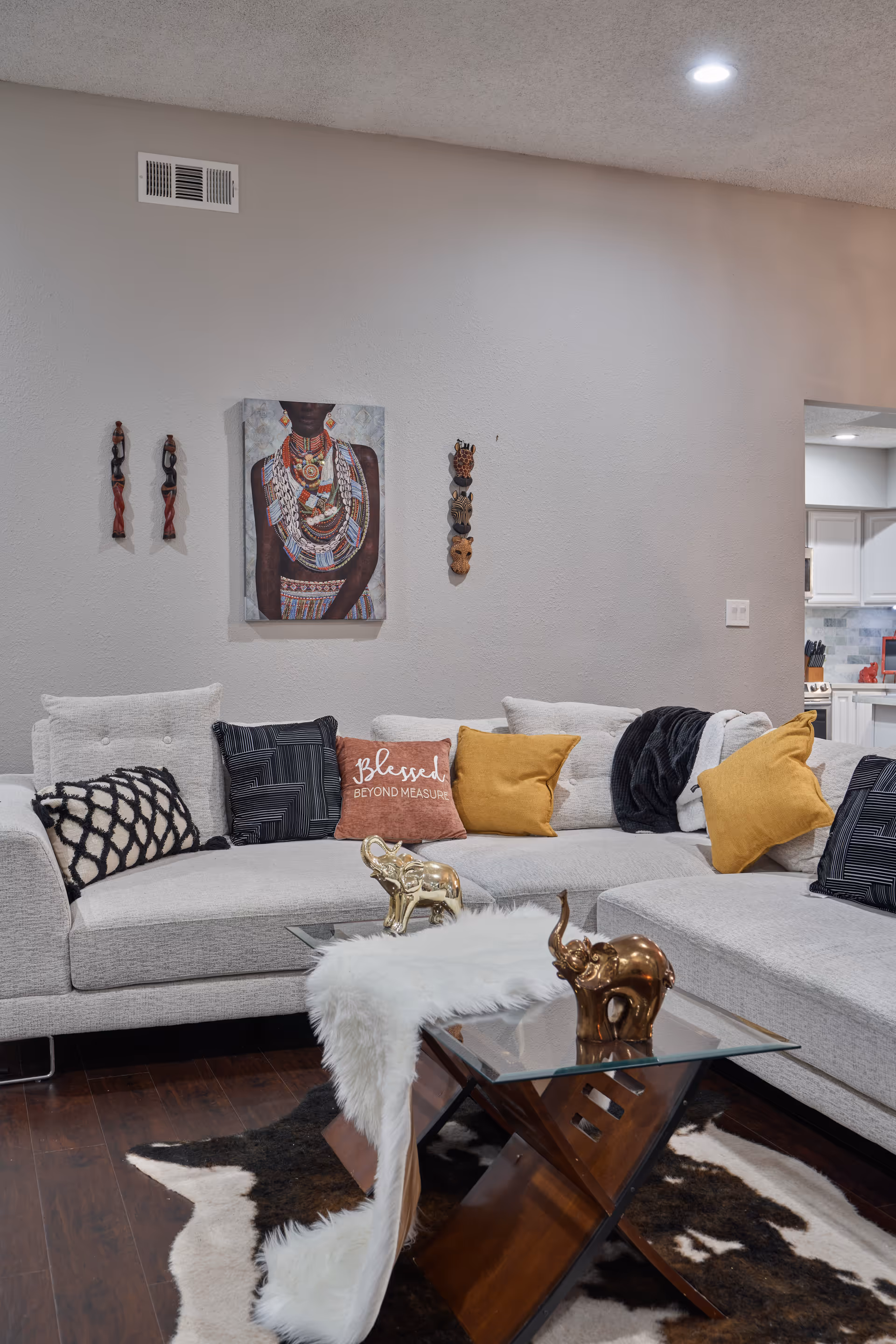 Cozy living room with a light-gray sectional, decorative pillows, and glass coffee table.