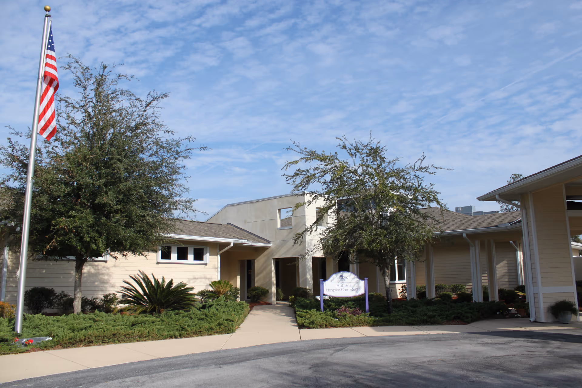 Front exterior view of Haven Roberts Hospice Care Center with flag and landscaping