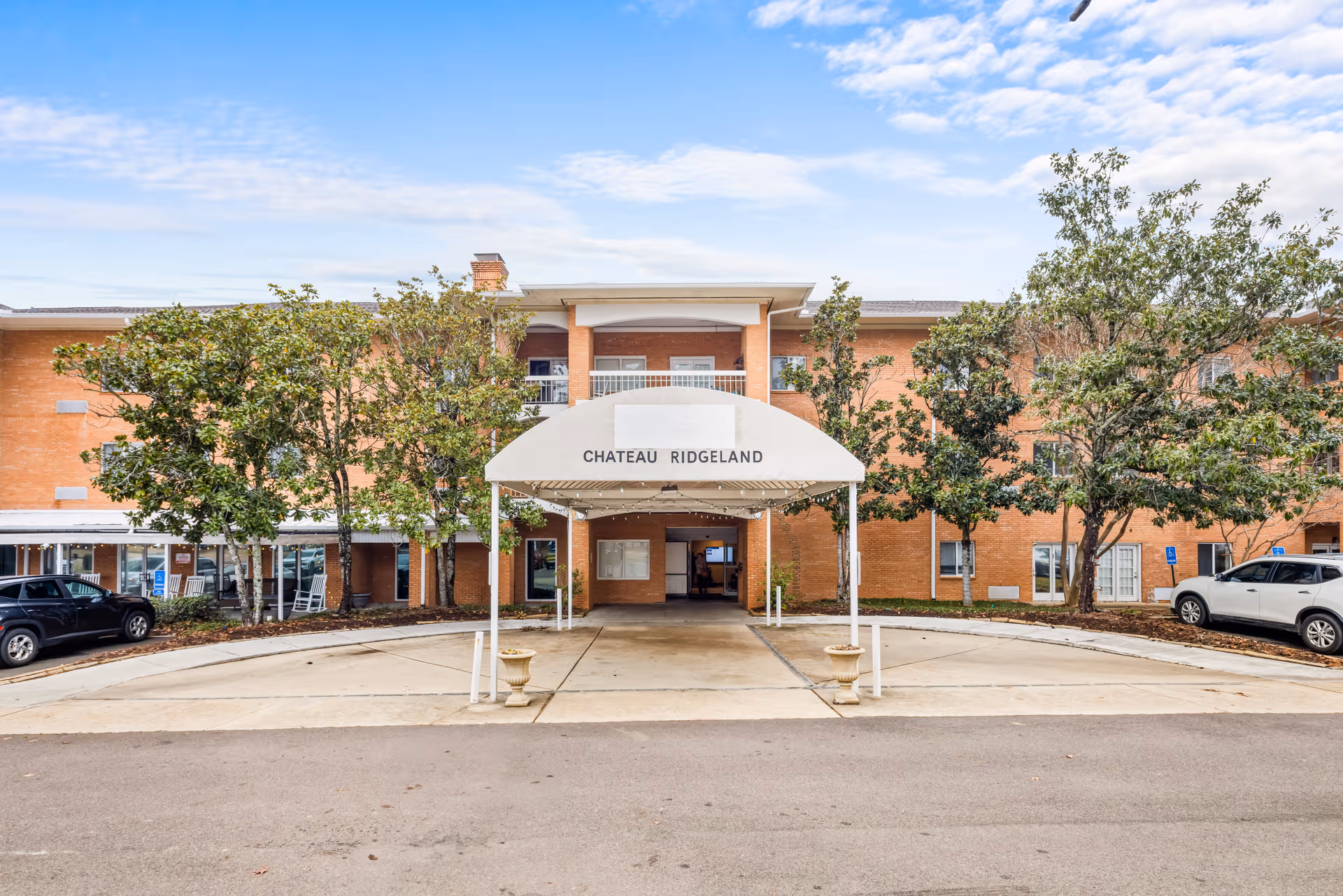Brick senior living facility entrance with a white canopy labeled Chateau Ridgeland.