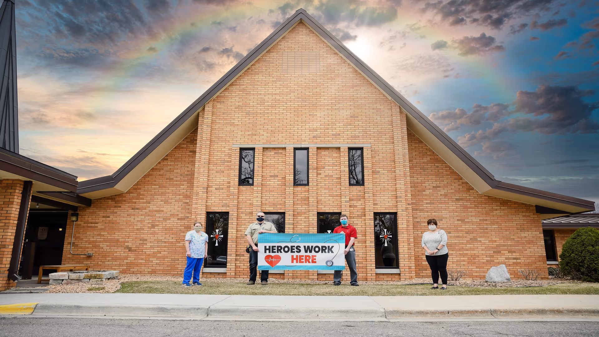 Exterior view of Vivie Corporate - Alexandria with five people holding a 'Heroes Work Here' banner.