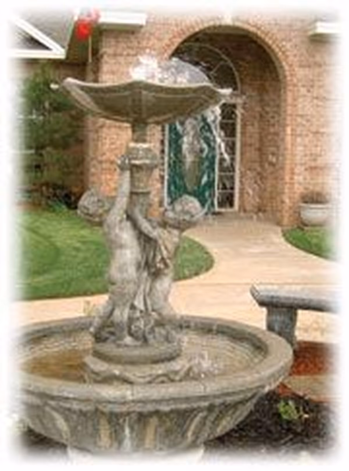 Stone tiered fountain with cherub statues in front of a brick building's arched entrance and walkway.