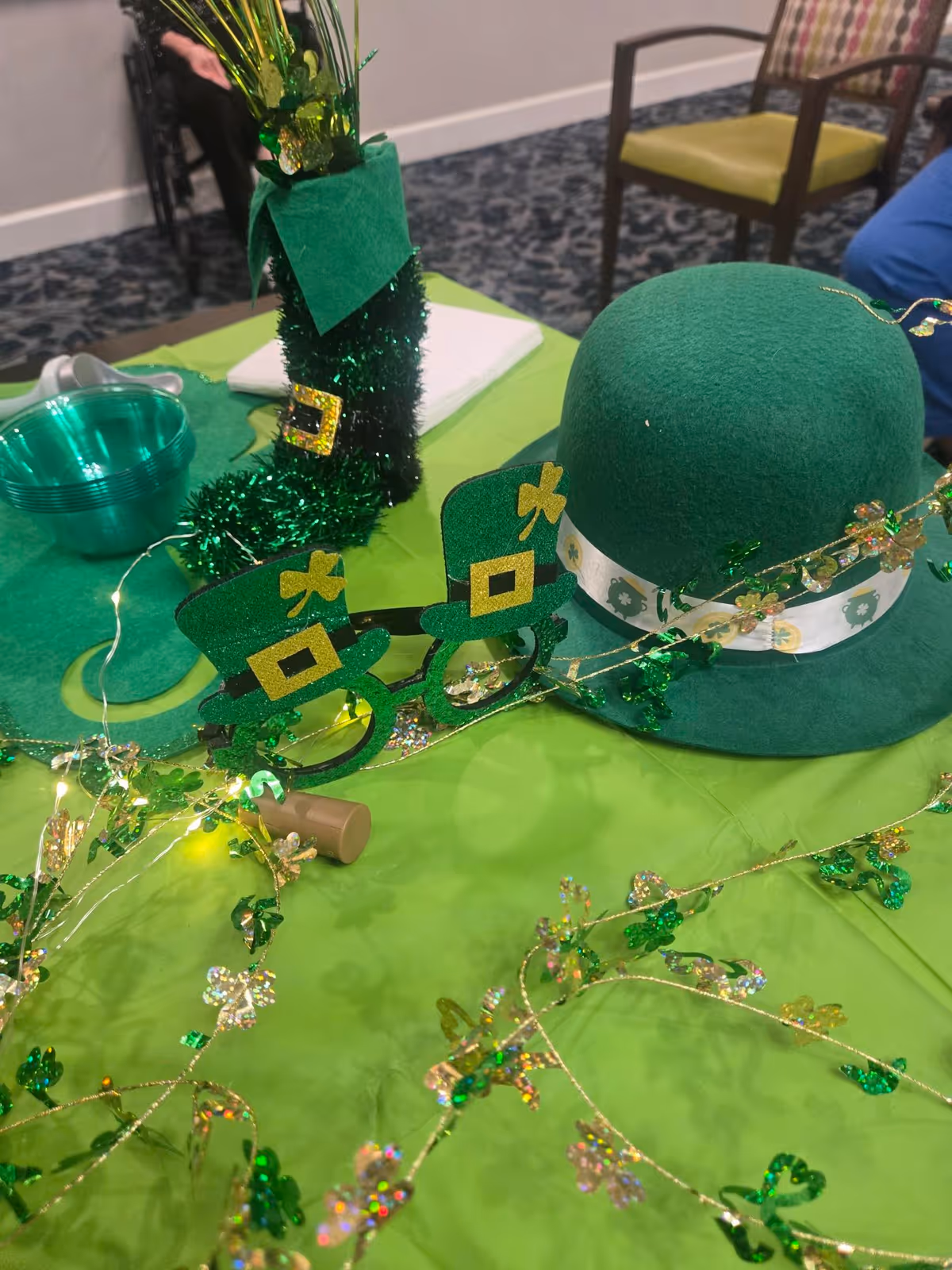 Green St. Patrick's Day table setting with hat, shamrocks, and garland decorations.