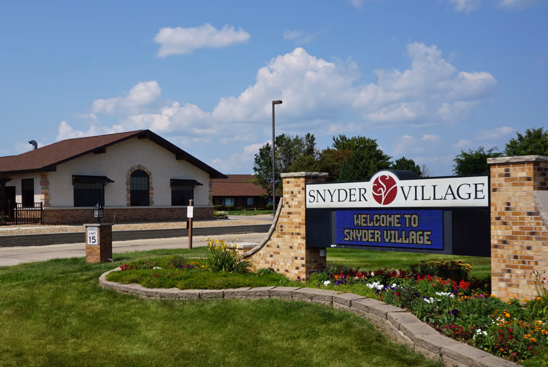 Exterior view of Snyder Village facility with sign and landscaped entrance.
