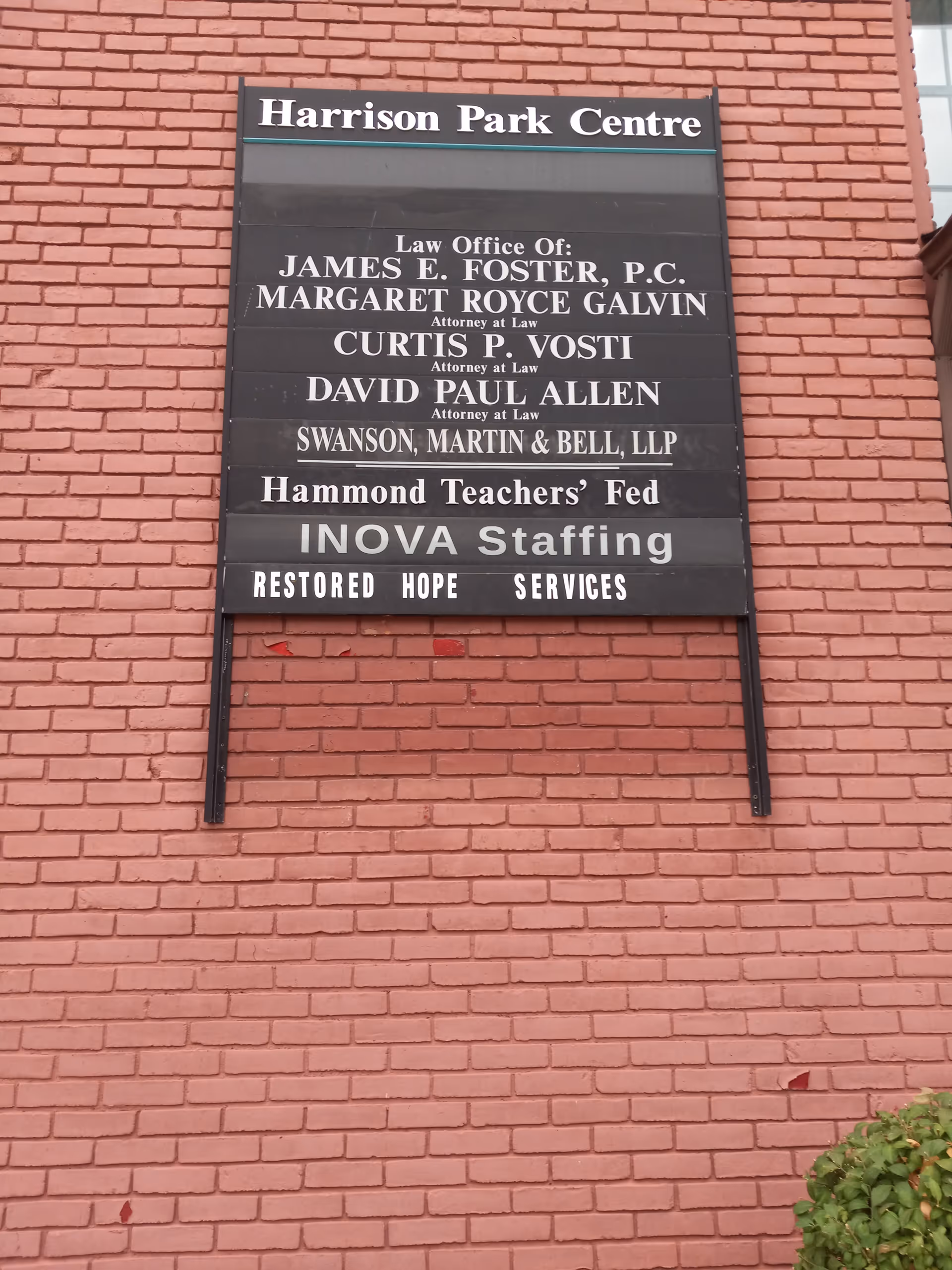 Signboard on red brick exterior lists Harrison Park Centre and tenants.