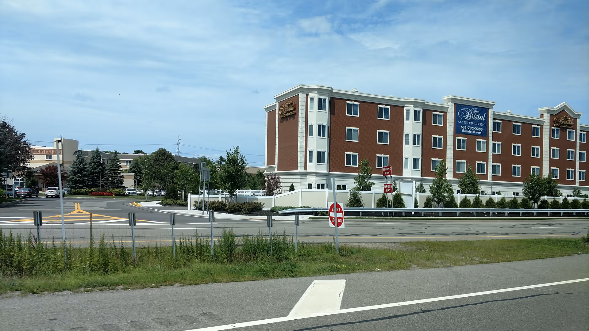 Exterior view of The Bristal Assisted Living at Holtsville along the road.