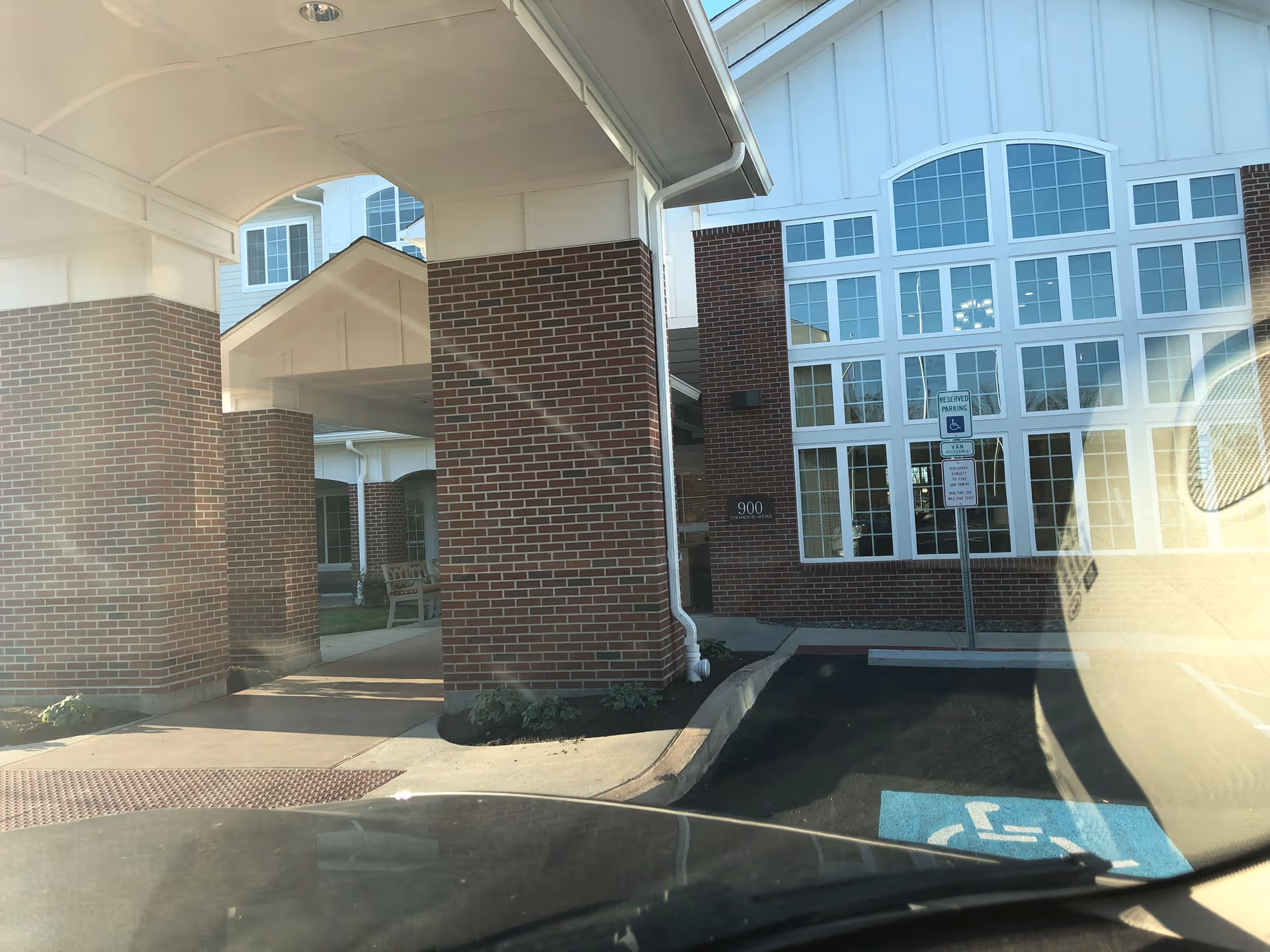 Brick building exterior featuring a covered entrance, tall windows, and brick columns.