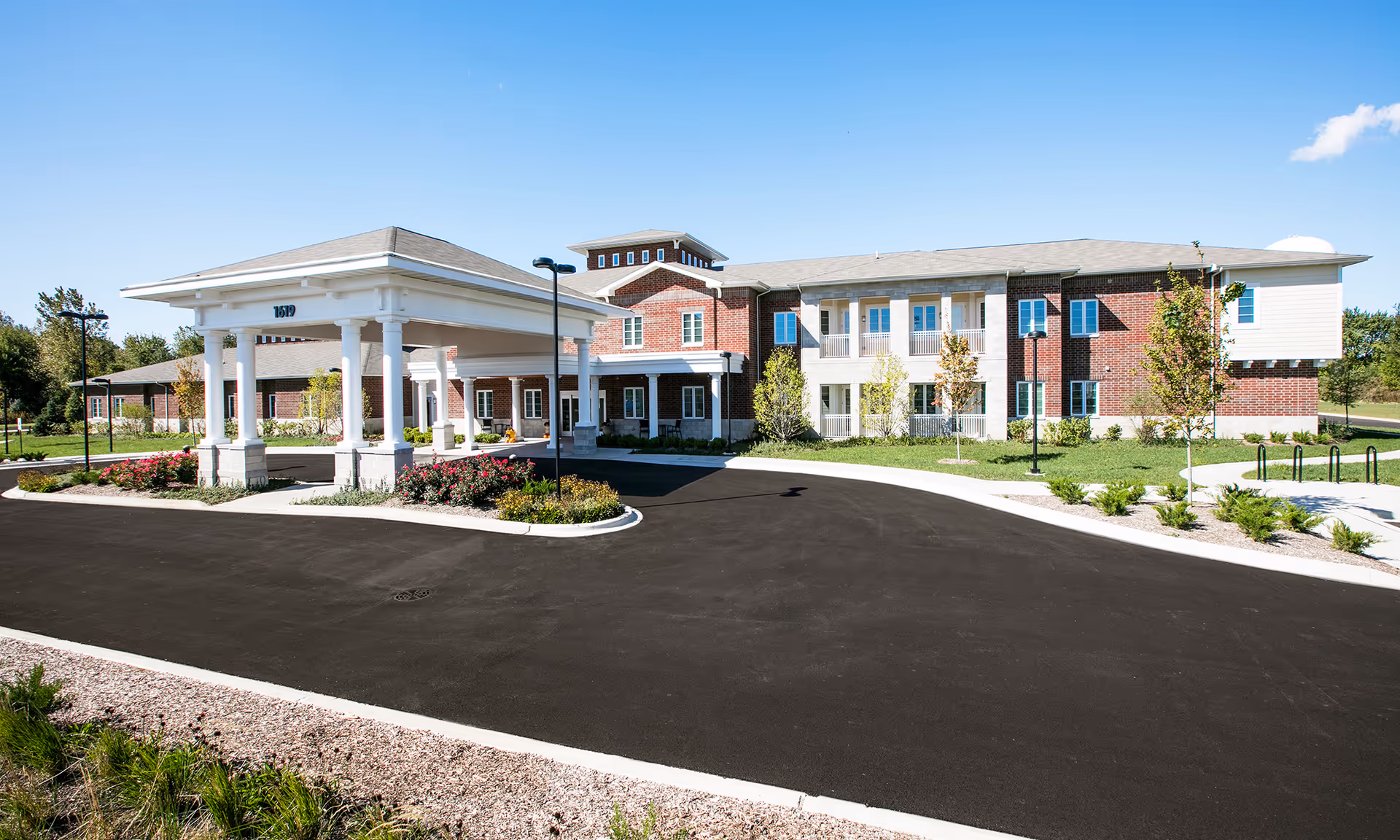 Exterior view of HarborChase of Naperville building with driveway and white porte-cochere.