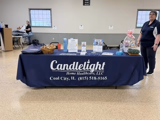 Indoor lobby scene with a Candlelight Home Healthcare bannered table and staff nearby.