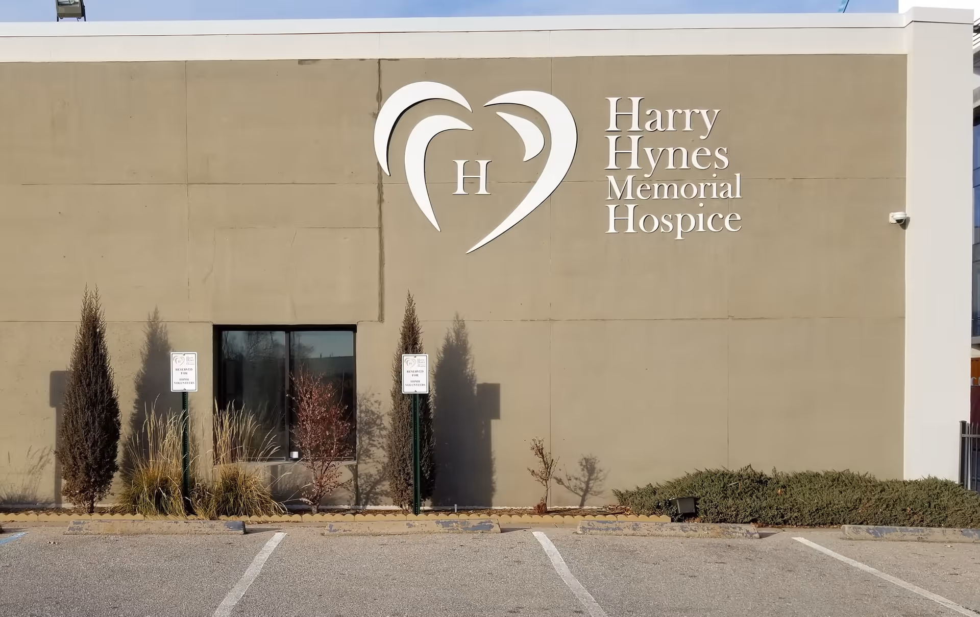 Front view of Harry Hynes Memorial Hospice building with large sign on beige wall