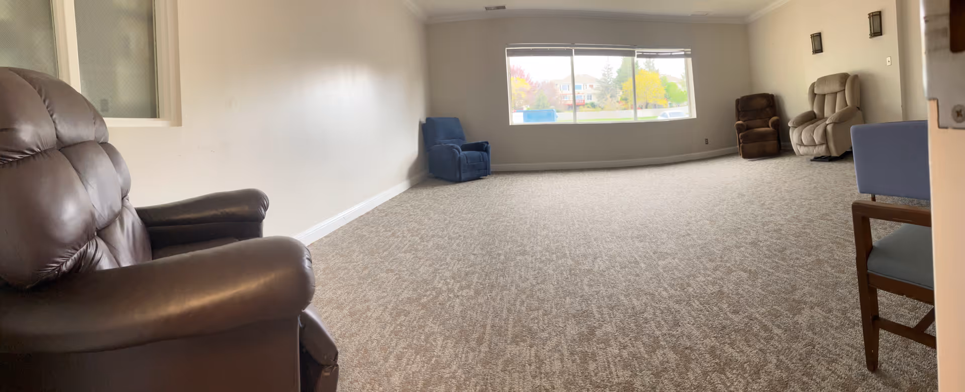 Spacious lounge at The Auberge at Aspen Park with recliners and a large window.
