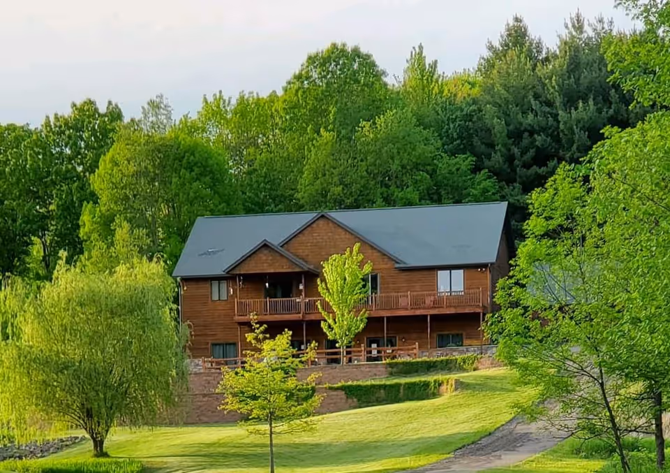 Lambs Creek West Adult Family Home exterior, a wooden two-story building among green trees.
